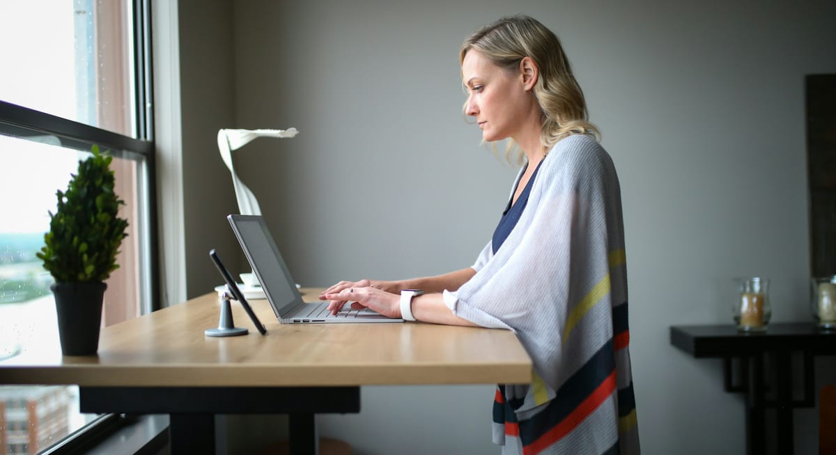 A woman working at a standing desk in a bright room
